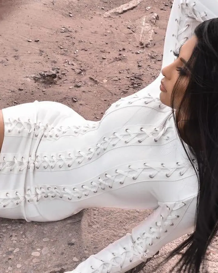 Femme en robe blanche ajustée, allongée sur un sol extérieur