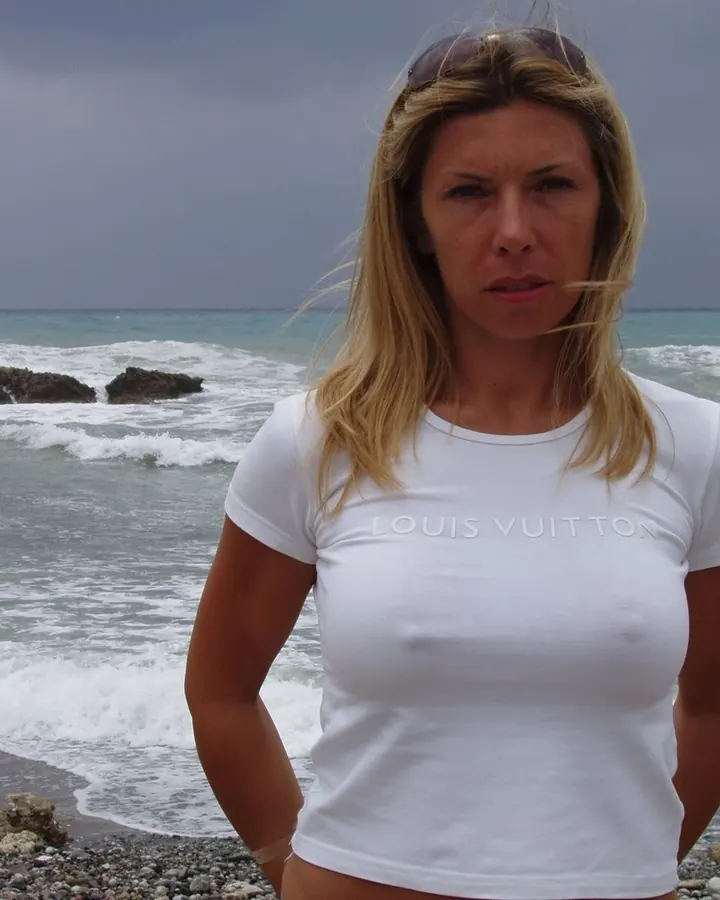 Femme aux cheveux châtains, portant une robe blanche, debout dans un jardin tropical.