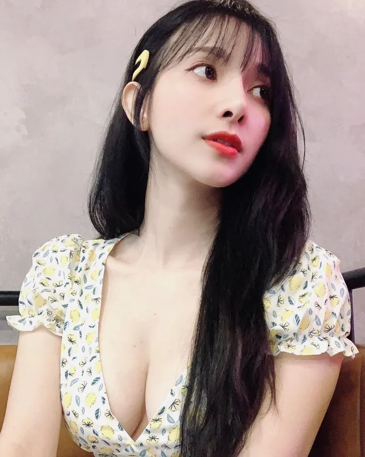 Femme asiatique aux cheveux noirs en robe à motifs jaunes, regardant de côté, avec un fond neutre