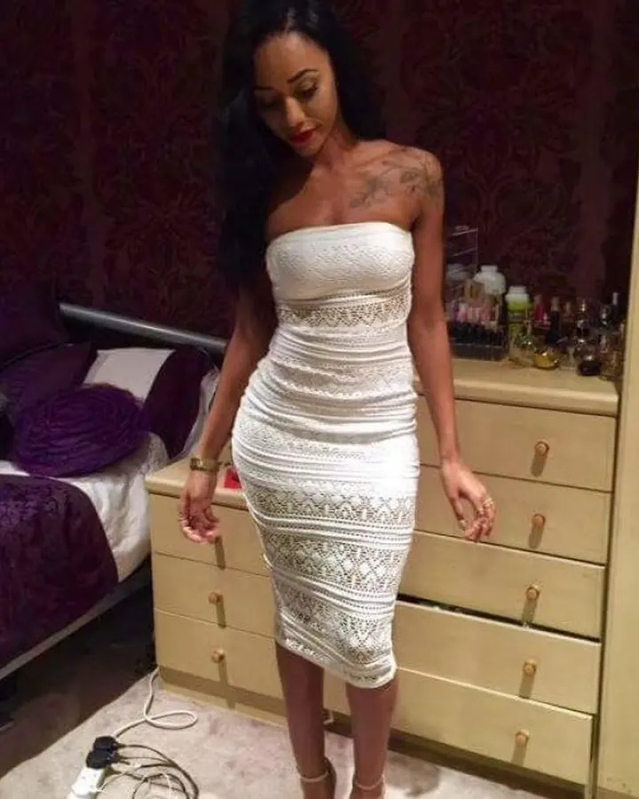 Femme aux cheveux noirs portant un soutien-gorge noir, tenant son doigt sur les lèvres, avec un collier en verre transparent.