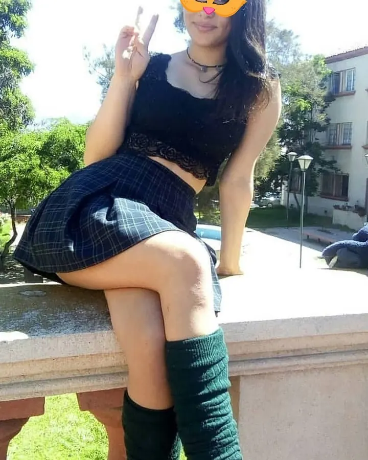 jeune femme brune en jupe écossaise assise sur un muret