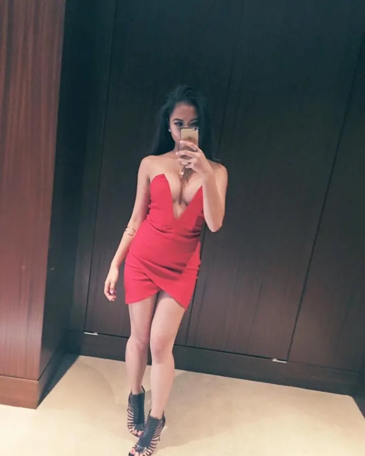Femme arabe aux cheveux bruns, portant un soutien-gorge blanc et des collants blancs, les bras derrière la tête, dans une lumière bleutée.