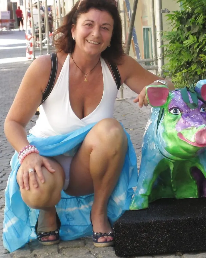 Femme européenne aux cheveux châtains, souriante, vêtue d'un haut noir, posant dans une chambre.