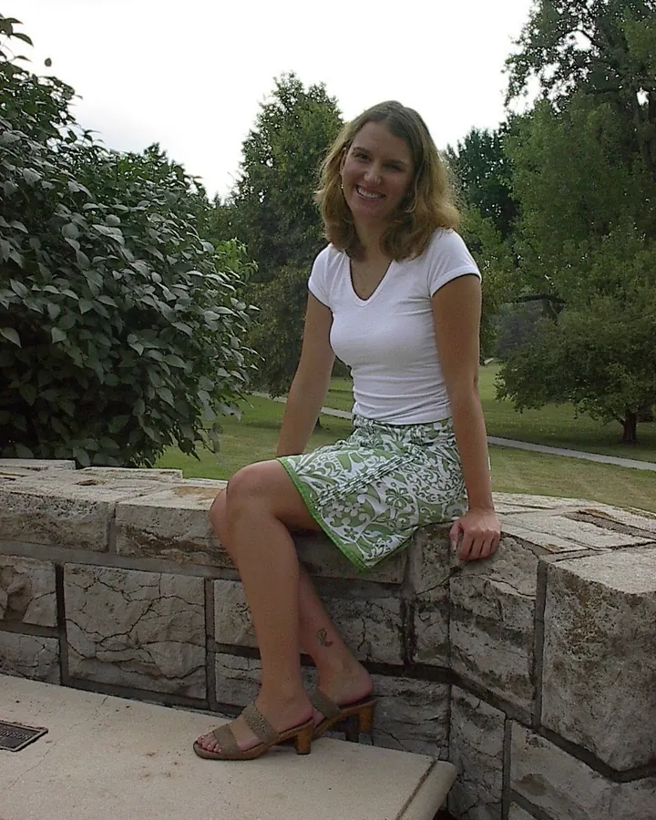 Femme blonde assise sur un muret en jupe verte