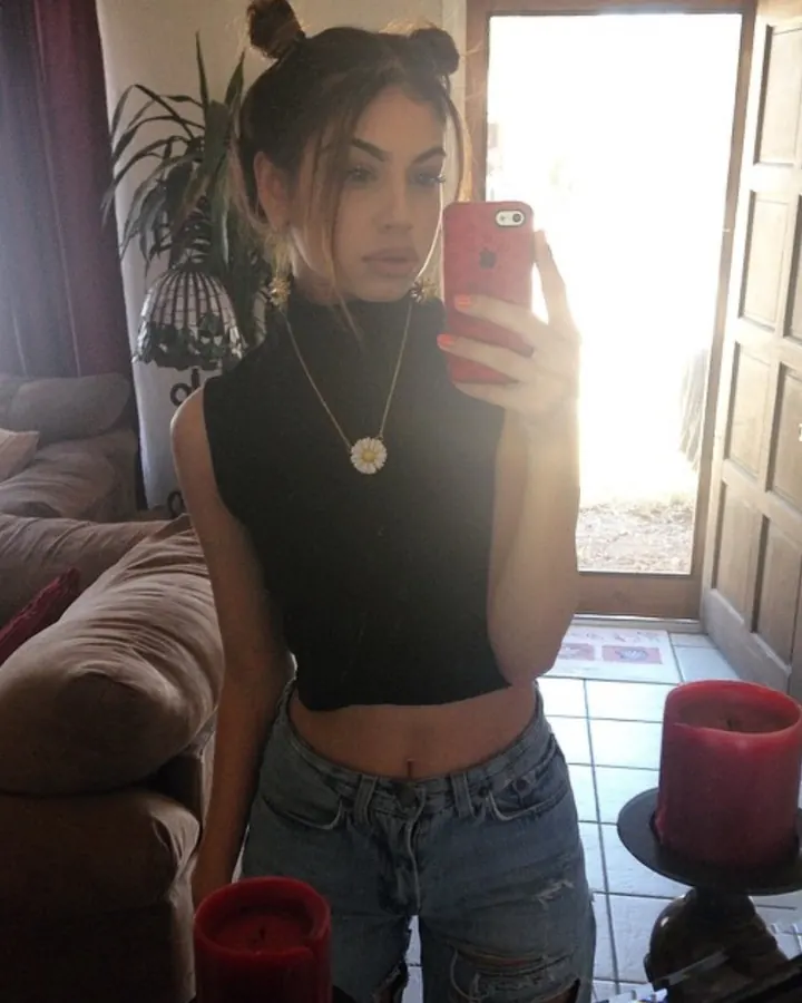 Femme en haut noir, prenant un selfie devant un miroir, avec des bougies rouges
