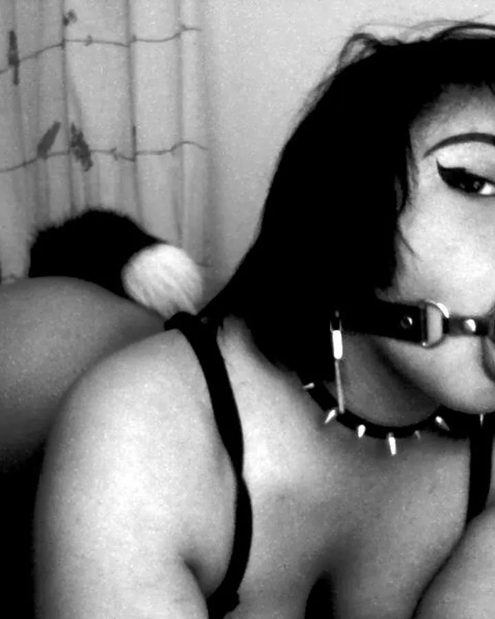 Femme en noir avec collier à pointes et bâillon, en noir et blanc